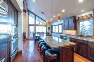 Kitchen with appliances with stainless steel finishes, a kitchen breakfast bar, light stone counters, a center island, and sink