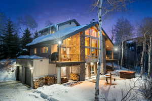 Snow covered property featuring a garage and stone siding