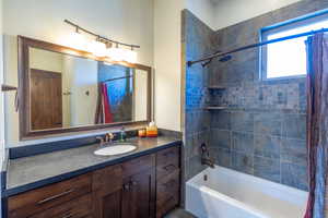 Bathroom featuring vanity and shower / bathtub combination with curtain