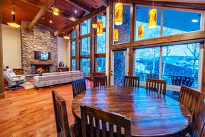 Dining area with a mountain view, a stone fireplace, wooden ceiling, hardwood / wood-style flooring, and beam ceiling