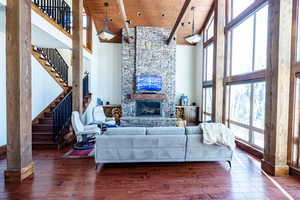 Living room featuring a fireplace, dark hardwood / wood-style floors, a towering ceiling, and wooden ceiling