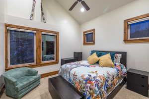 Carpeted bedroom with vaulted ceiling and ceiling fan