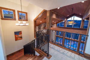 Stairs featuring hardwood / wood-style flooring, wooden ceiling, a chandelier, and lofted ceiling