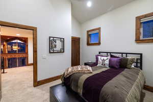 Bedroom with high vaulted ceiling and light colored carpet