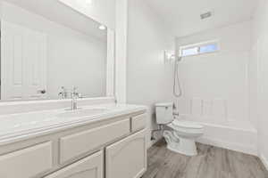 Full bath featuring toilet, vanity, wood finished floors, baseboards, and shower / washtub combination