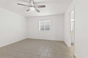 Unfurnished room featuring a ceiling fan, light tile patterned flooring, and baseboards