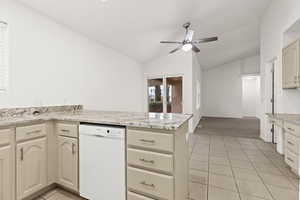 Kitchen featuring dishwasher, vaulted ceiling, a peninsula, light tile patterned flooring, and ceiling fan