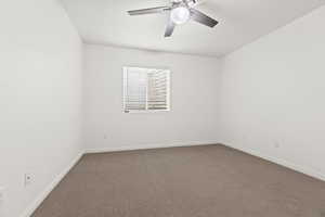 Carpeted empty room featuring a ceiling fan and baseboards