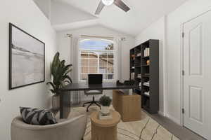 Home office featuring lofted ceiling, a ceiling fan, light colored carpet, and baseboards