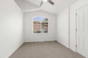 Empty room featuring a ceiling fan, carpet flooring, vaulted ceiling, and baseboards