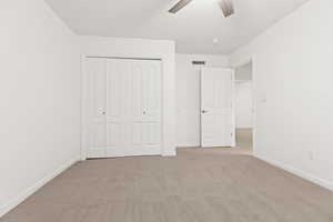 Unfurnished bedroom with a closet, light carpet, and baseboards