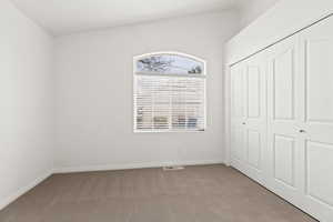 Unfurnished bedroom with carpet flooring, a closet, and baseboards