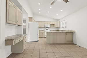 Kitchen with white appliances, vaulted ceiling, ceiling fan, recessed lighting, and light tile patterned floors