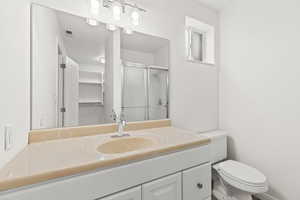 Bathroom featuring toilet, vanity, and an enclosed shower
