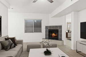 Living room with light tile patterned flooring, a fireplace, ceiling fan, and baseboards