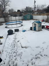 Snowy yard with a shed and a trampoline