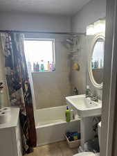 Bathroom with tile patterned floors, toilet, a textured ceiling, and shower / bath combination with curtain