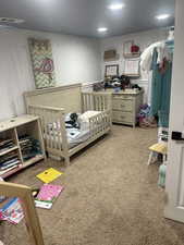 Carpeted bedroom featuring a nursery area