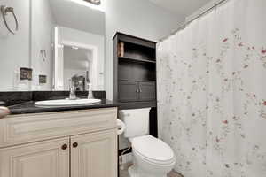 Bathroom featuring vanity, curtained shower, and toilet