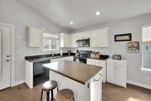 Kitchen with white cabinets, a center island, sink, and black appliances