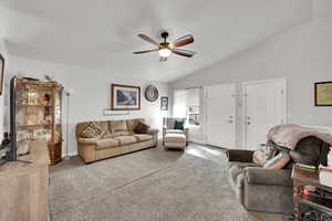 Carpeted living room with vaulted ceiling, ceiling fan, and a textured ceiling