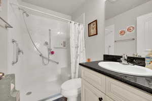 Bathroom with a textured ceiling, toilet, vanity, and curtained shower