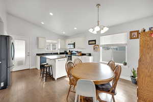 Dining room with an inviting chandelier, dark hardwood / wood-style floors, a wealth of natural light, and lofted ceiling