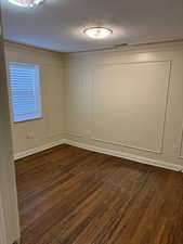 Unfurnished room featuring dark hardwood / wood-style flooring and a textured ceiling