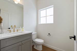 Bathroom featuring toilet, vanity, and wood-type flooring