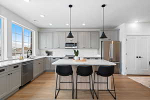 Kitchen featuring appliances with stainless steel finishes, a kitchen island, and decorative light fixtures