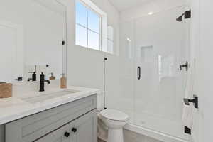 Bathroom featuring toilet, vanity, and an enclosed shower