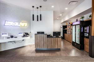 Kitchen featuring dark wood-type flooring, black fridge, and hanging light fixtures