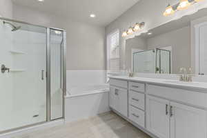 Bathroom featuring separate shower and tub and vanity