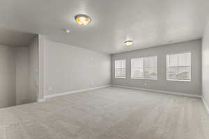 Spare room with light carpet and a textured ceiling