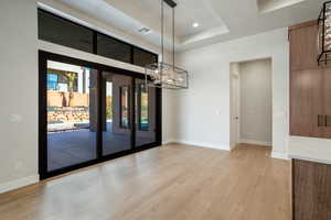 Unfurnished room with light hardwood / wood-style floors, a chandelier, and a tray ceiling