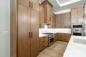 Kitchen featuring light stone countertops, light hardwood / wood-style floors, sink, appliances with stainless steel finishes, and decorative backsplash