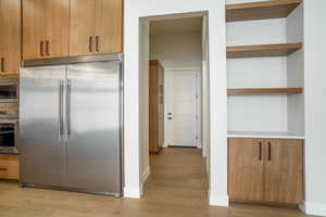 Kitchen with built in appliances and light hardwood / wood-style floors