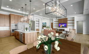 Dining room featuring a tray ceiling, sink, light hardwood / wood-style floors, and built in features