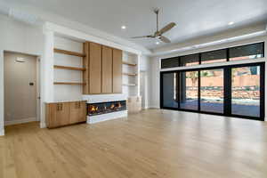 Unfurnished living room with ceiling fan, a high end fireplace, and light hardwood / wood-style floors