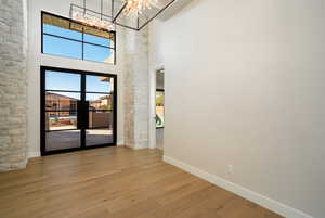 Unfurnished room featuring hardwood / wood-style floors, a wealth of natural light, a chandelier, and a high ceiling