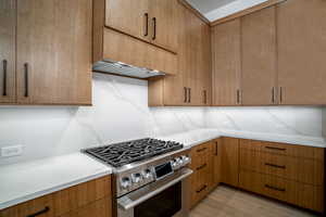 Kitchen featuring light hardwood / wood-style floors, stainless steel gas range, and backsplash