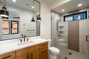 Bathroom with toilet, vanity, and an enclosed shower