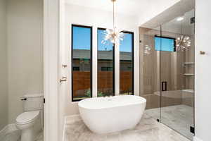 Bathroom featuring separate shower and tub, a chandelier, and toilet