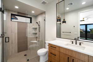 Bathroom featuring tile patterned flooring, toilet, ceiling fan, vanity, and walk in shower