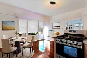 Kitchen with stainless steel range with gas cooktop, baseboards, dark wood-type flooring, and light countertops