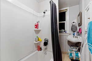 Bathroom with shower / tub combo with curtain and tile patterned floors