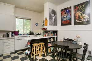 Kitchen with light flooring, light countertops, white cabinets, ornamental molding, and a breakfast bar