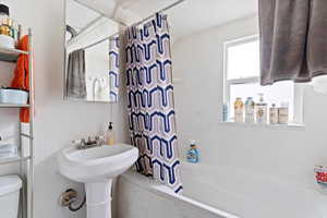 Bathroom with shower / bathtub combination with curtain and toilet