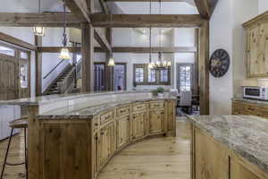 Kitchen with pendant lighting, a breakfast bar, light stone countertops, and beam ceiling