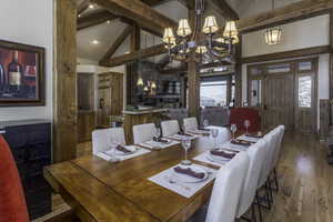 Dining room featuring hardwood / wood-style flooring, high vaulted ceiling, beamed ceiling, and a chandelier